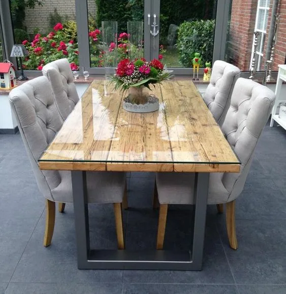 Glass Dinner Table On Top Of Wood Slab With Metal Base And Cusioned Chairs