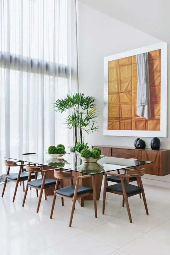 Glass Dinner Table With Plant Centerpiece And Cusioned Wood Chairs