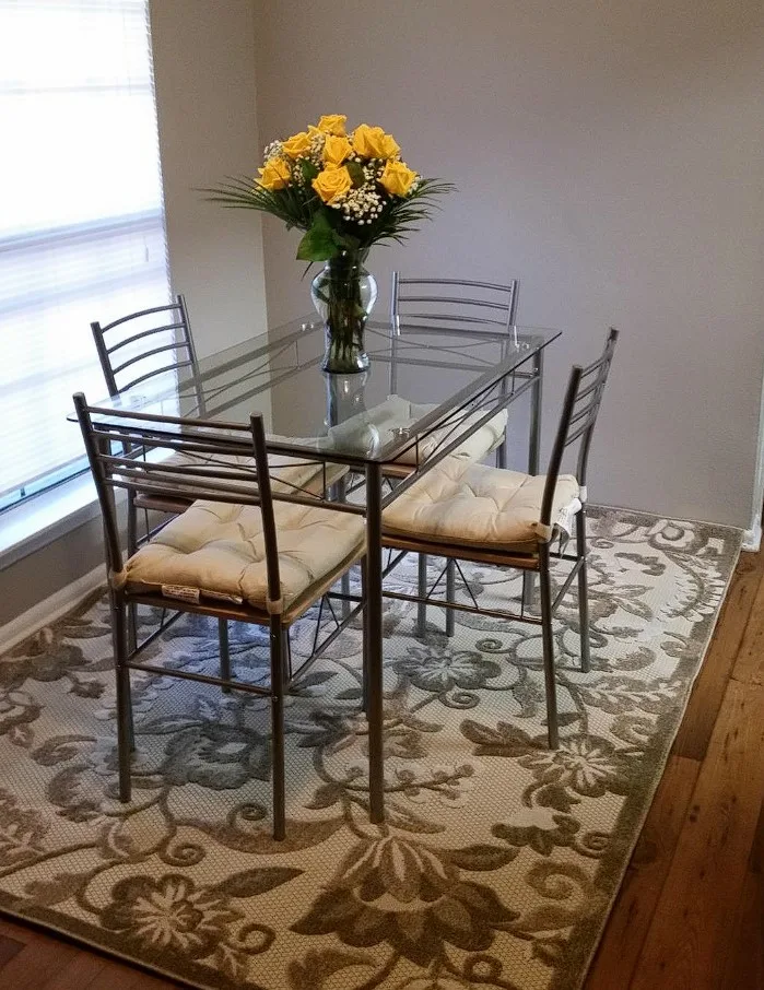 Glass Top Dining Table With Silver Metal Base And Cusioned Chairs
