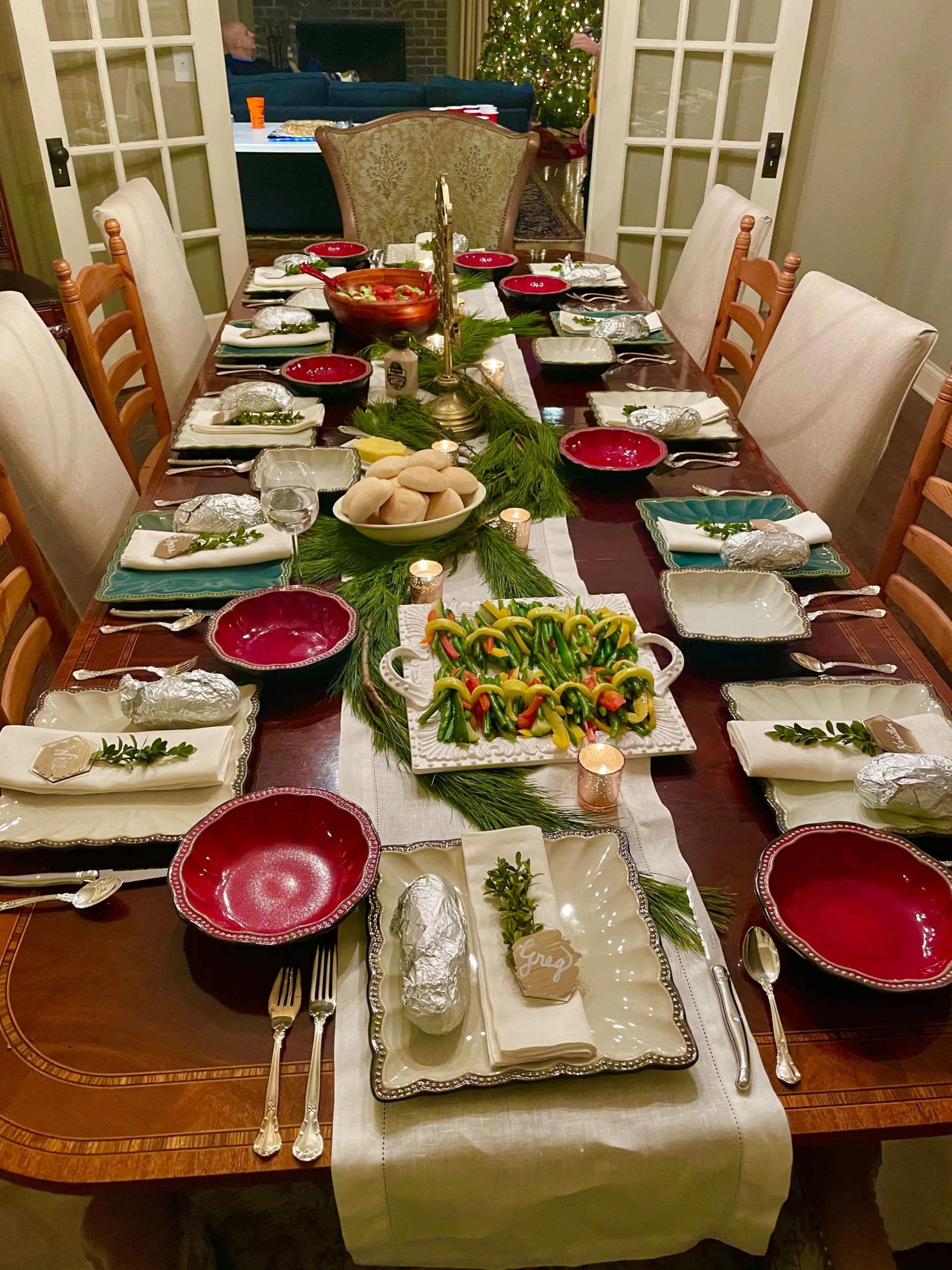 White Tablerunner Red Bowls Green Pine Leaves Garland Centerpiece Bread Christmas Tree Angle View Dining Tables